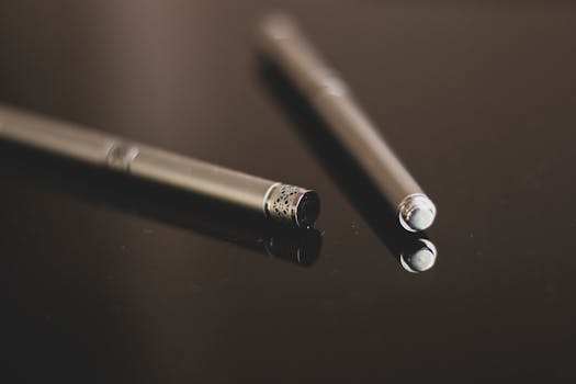 特写图像展示了一支光滑金属笔在反光表面上，突显现代设计