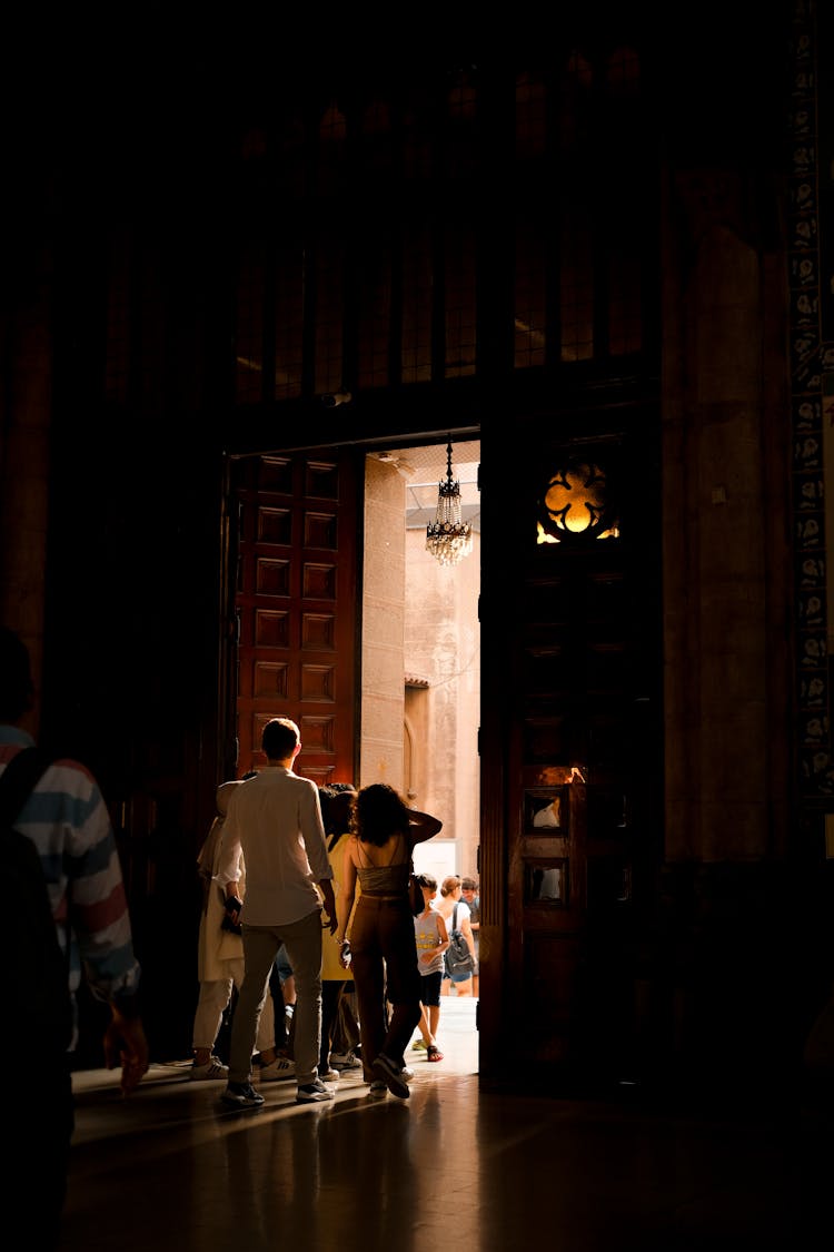 People Exiting A Church To A Sunlit Street