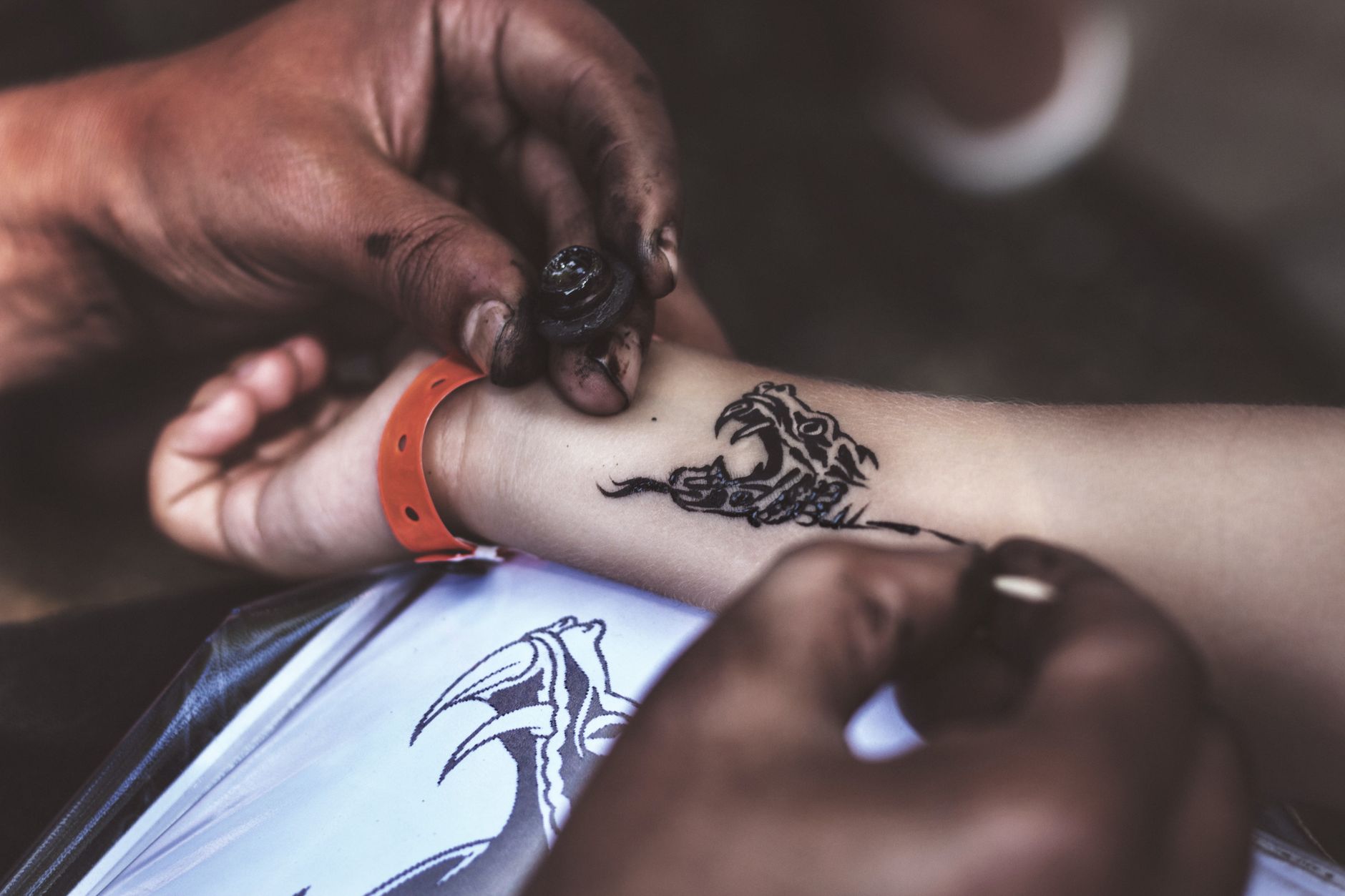 Close-up of hands carefully applying a moon phase temporary tattoo to wrist skin
