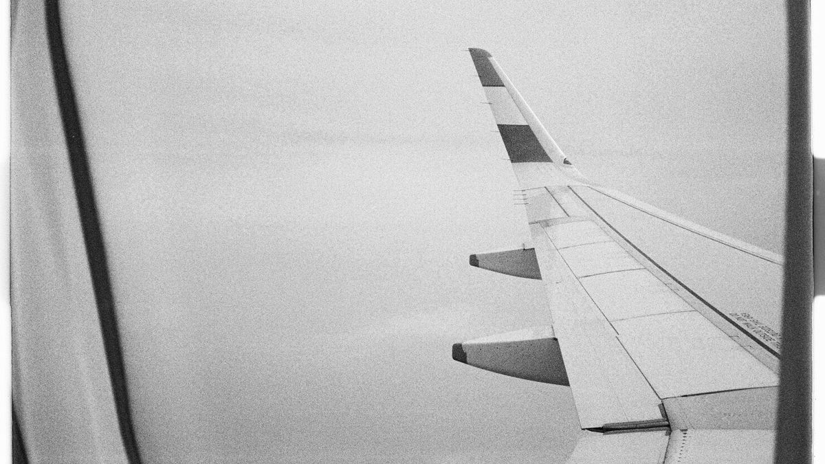 Black and white aerial view of an aircraft wing from a window seat.