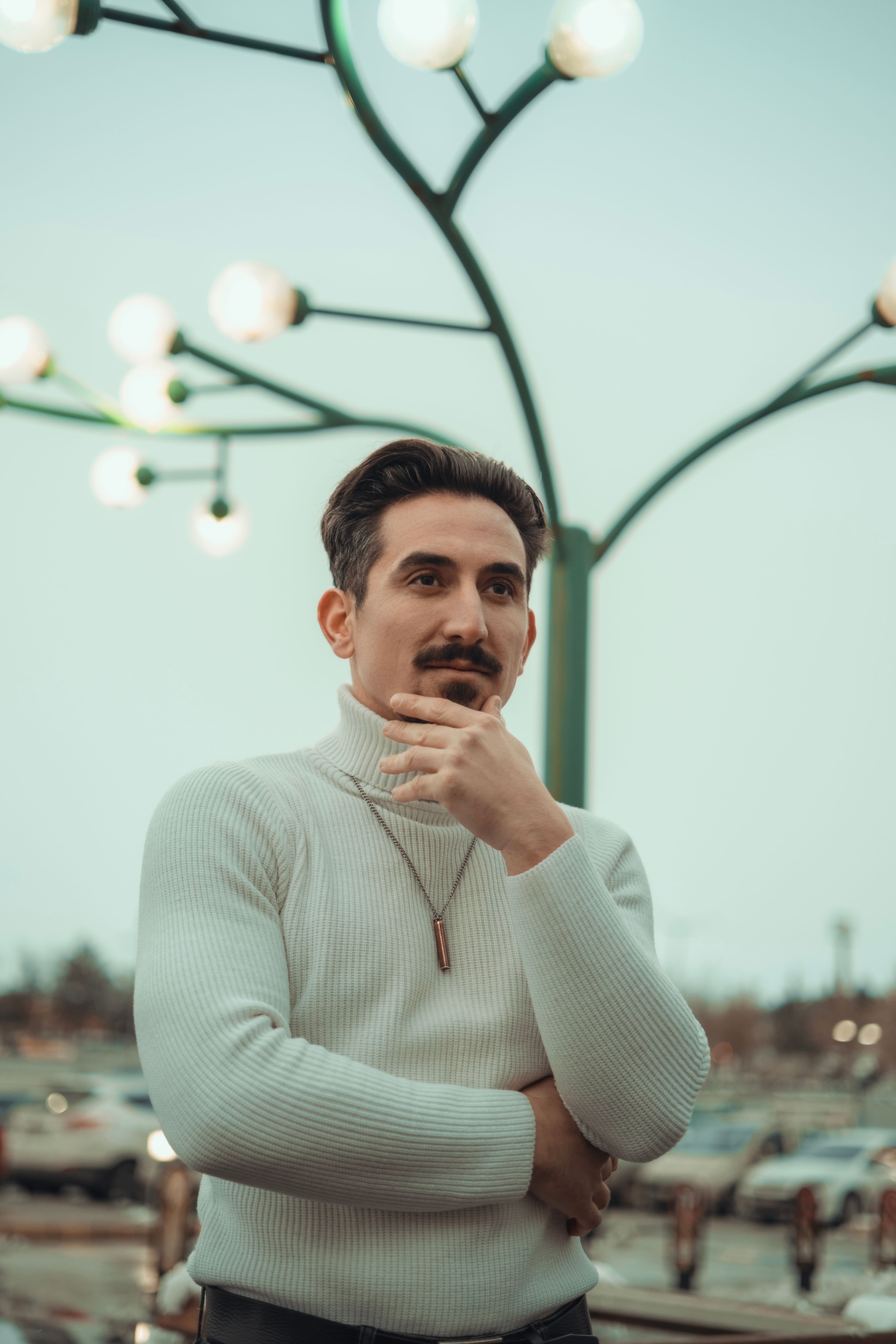 Stylish man in a turtleneck posing confidently against a city backdrop.