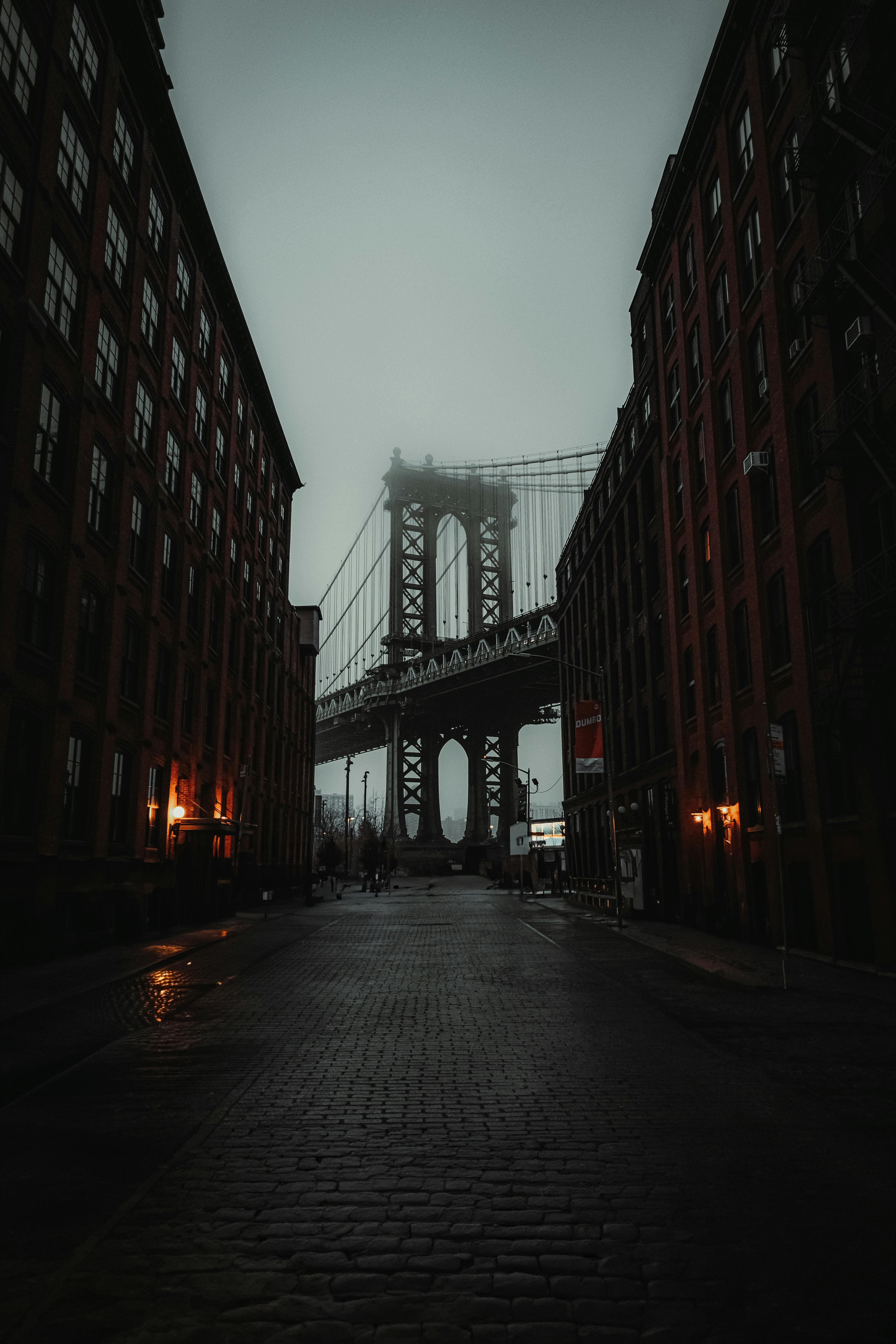 A misty view of the Manhattan Bridge framed by towering buildings in New York City.