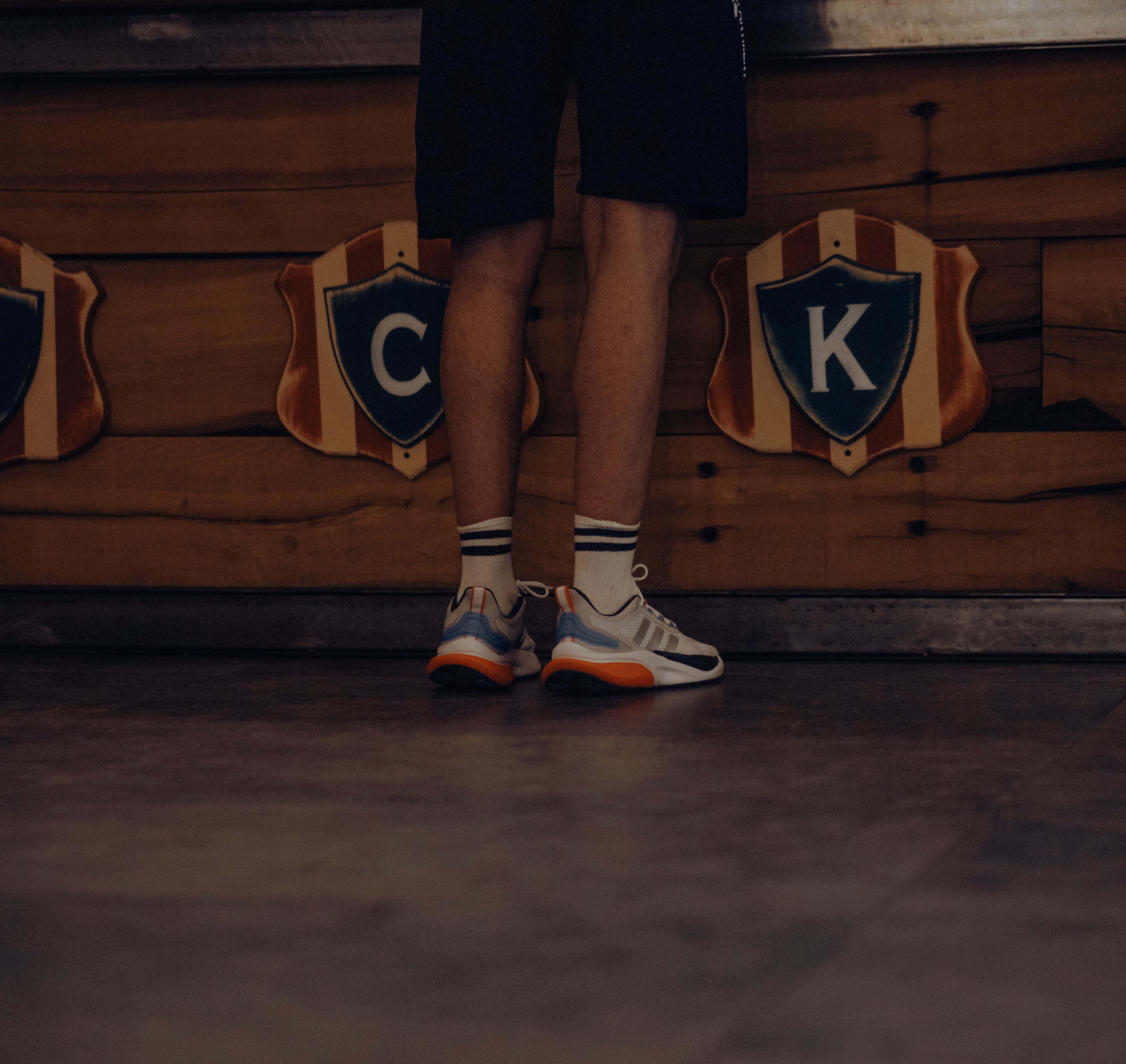 Back view of a man standing indoors by shields on a wooden wall.