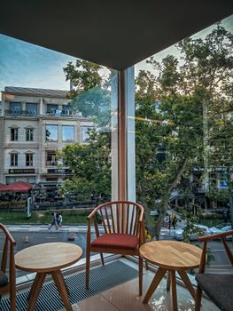 Cozy café interior with chairs and tables overlooking urban street.