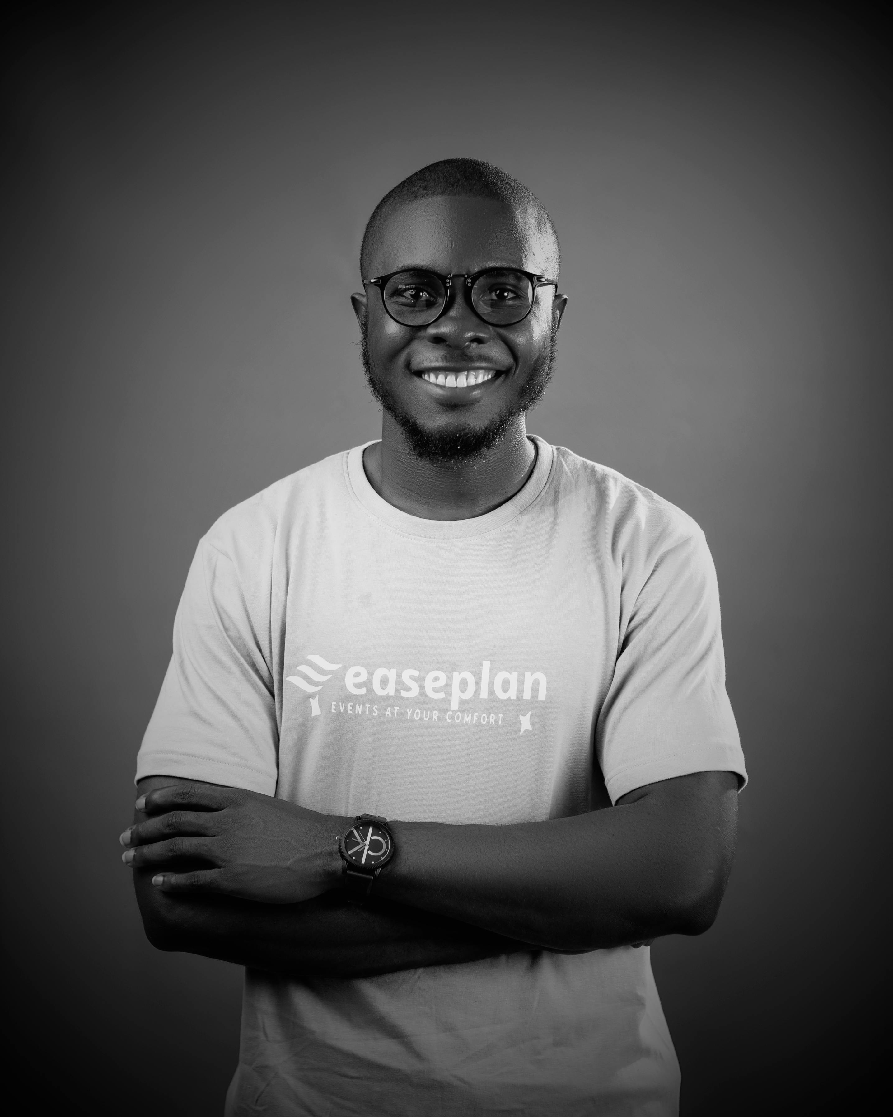 Black and white portrait of a smiling man wearing glasses with arms crossed.