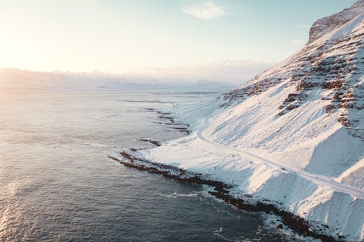 Stunning aerial view of a snow-covered coastal mountain at sunrise, showcasing the beauty of winter nature.