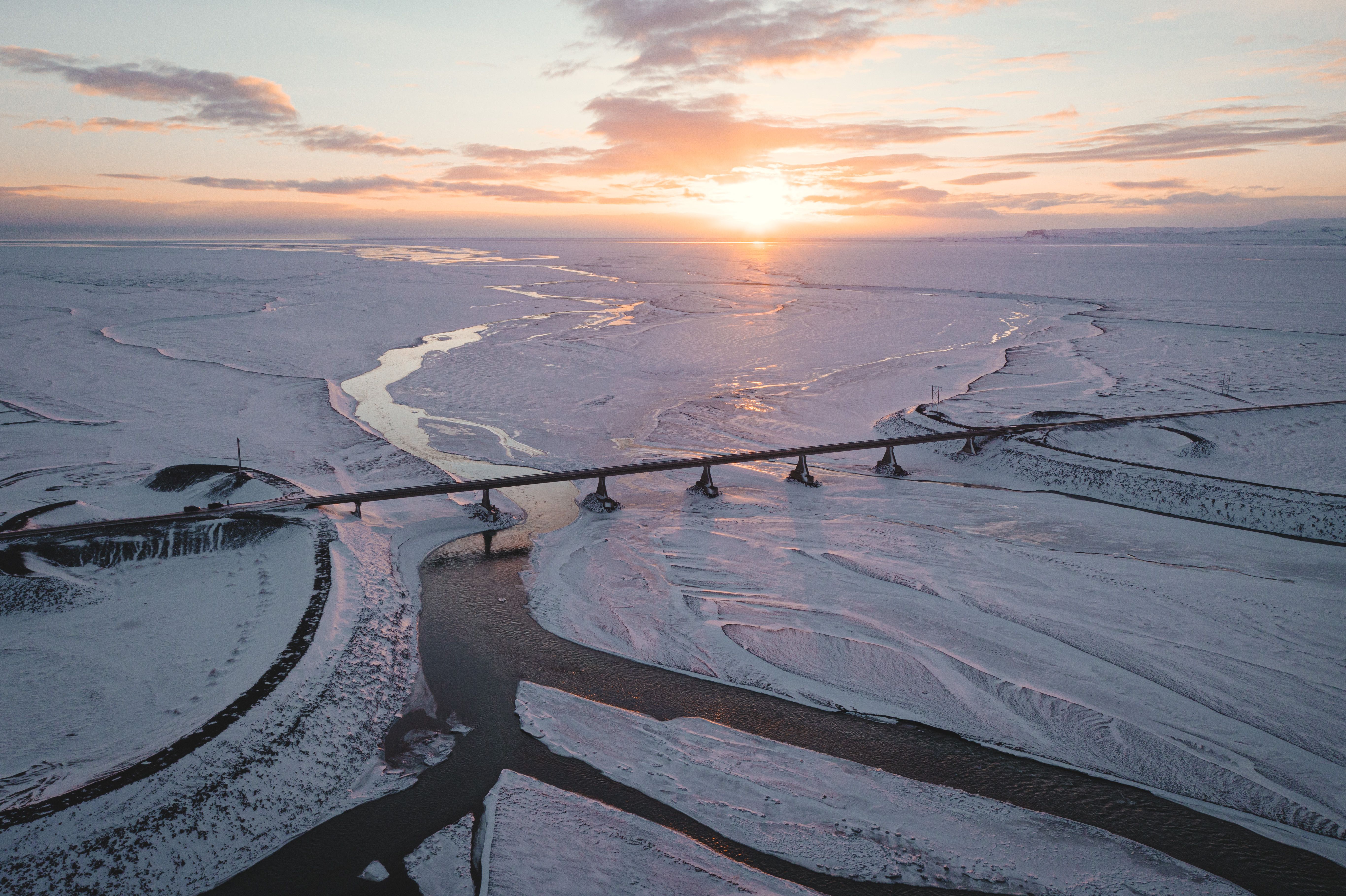 The sun is setting over a bridge in the middle of a frozen river · Free ...