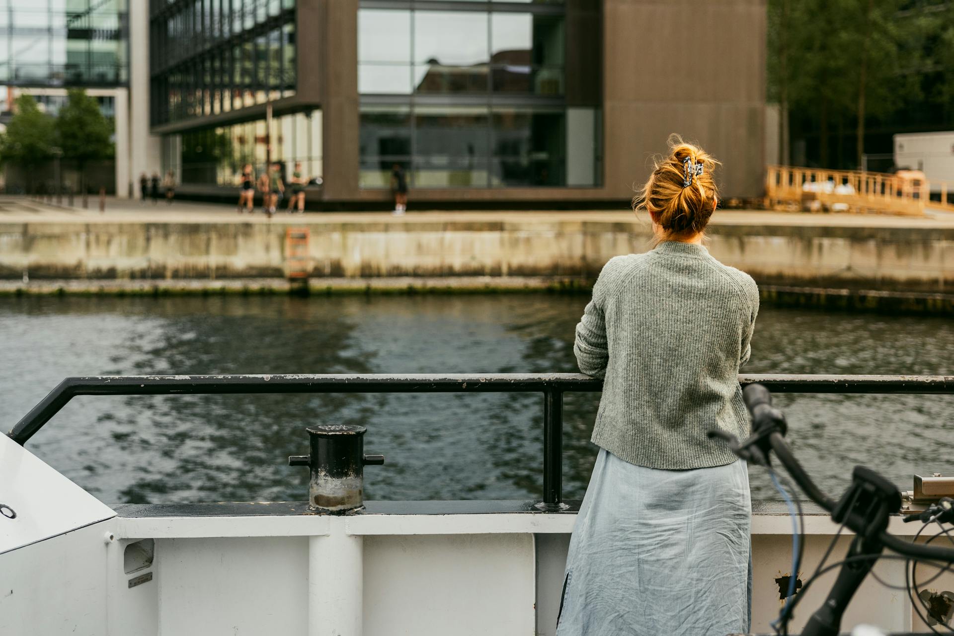 A woman gazes at urban architecture along the Copenhagen waterfront.