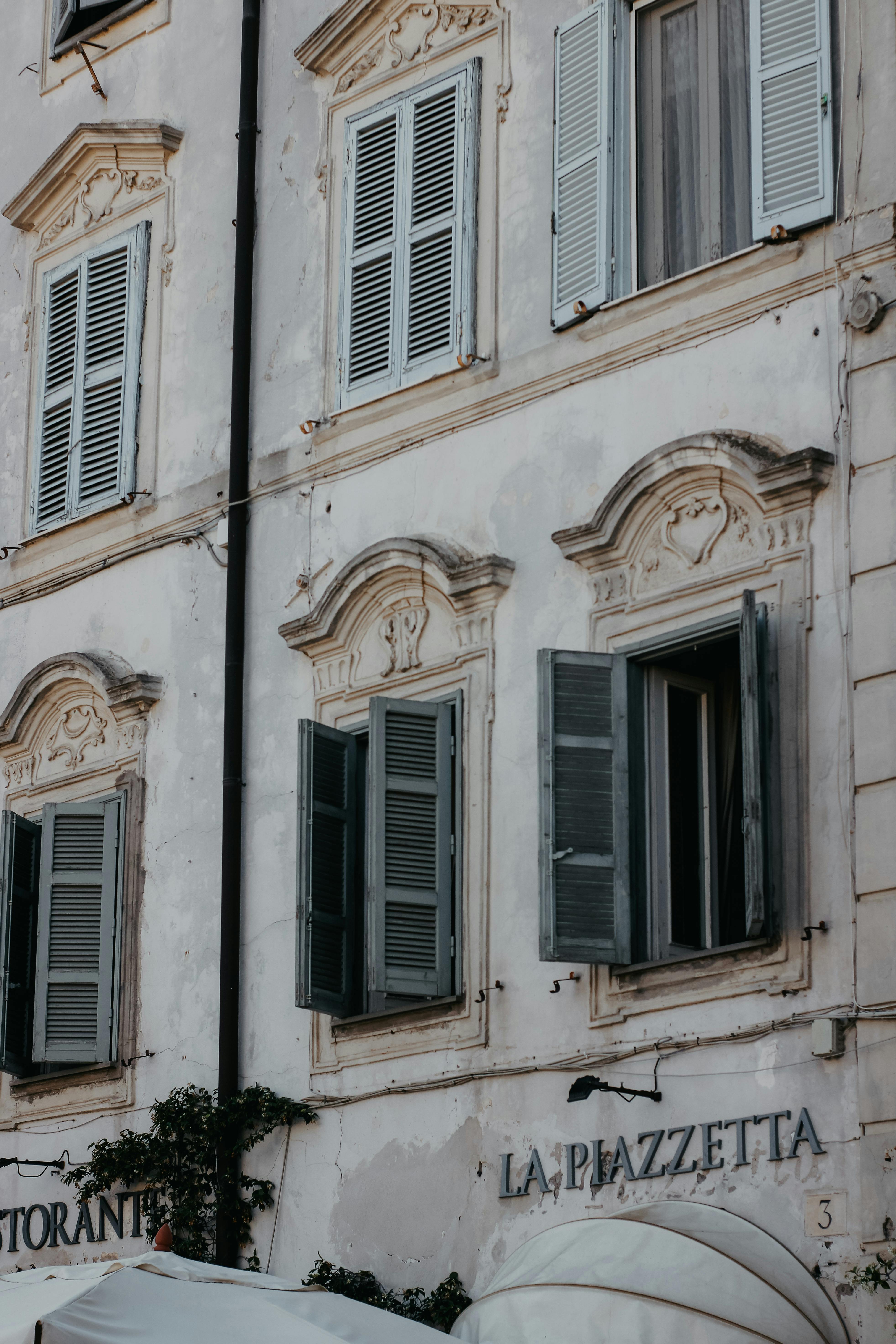 Elegant facade of a neoclassical building with decorative shutters in an urban setting.