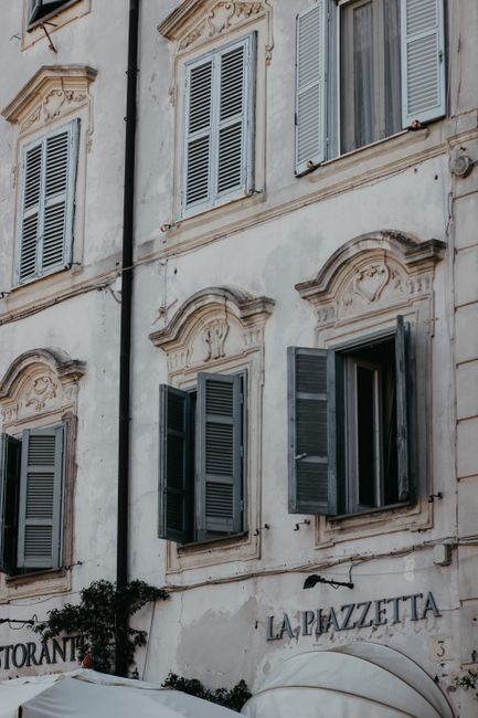 Elegant facade of a neoclassical building with decorative shutters in an urban setting.