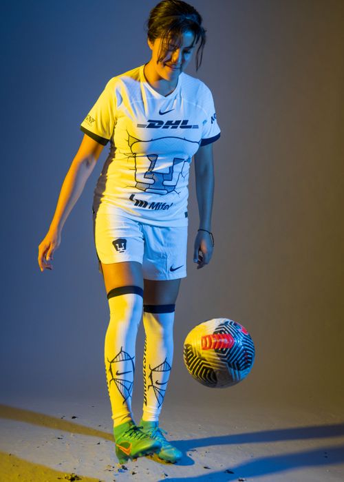 Free A sportswoman in sportswear expertly balances a soccer ball in an indoor setting. Stock Photo