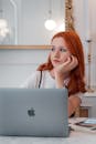 Red Haired Woman Sitting at Desk with Laptop