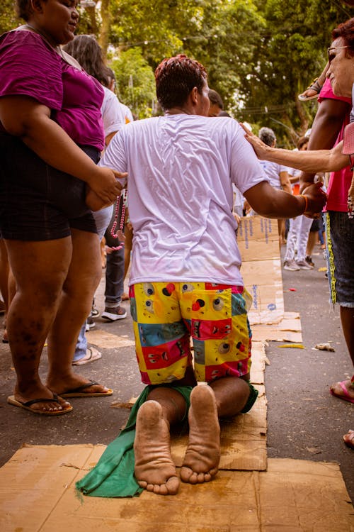 Man in White T-Shirt Kneeling During Ceremony on Street