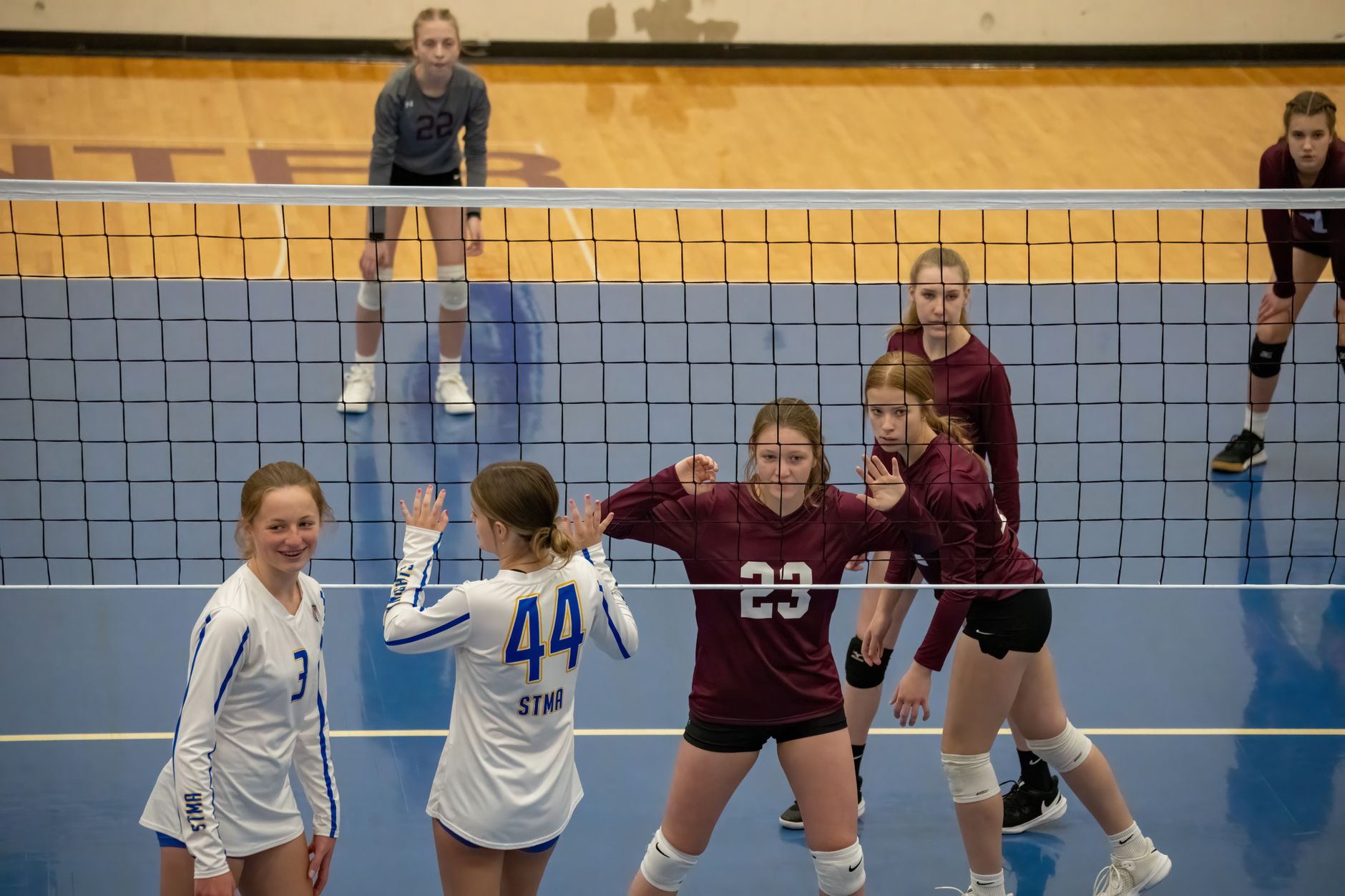 Teen girls playing volleyball indoors in Rochester, MN, showcasing teamwork and competition.