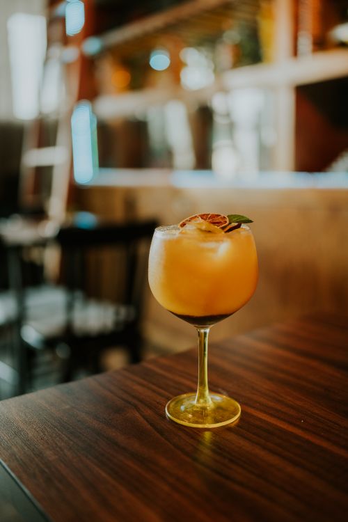 Free An elegant citrus cocktail garnished with dried fruit in a stylish glass on a wooden table. Stock Photo