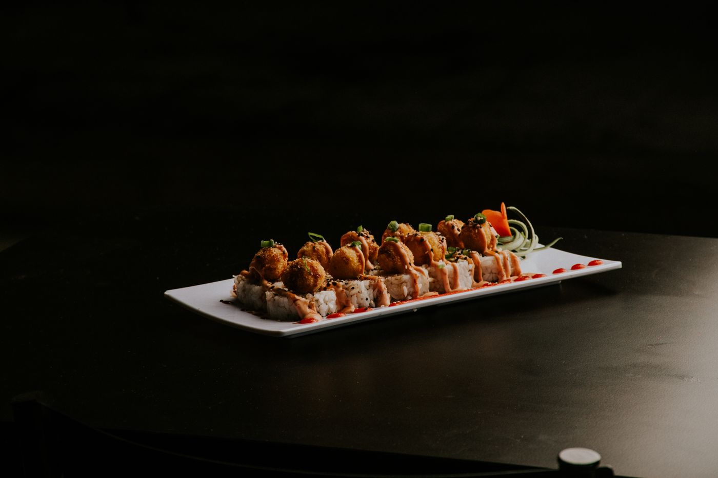 Sushi roll with crispy tempura topping on a black background