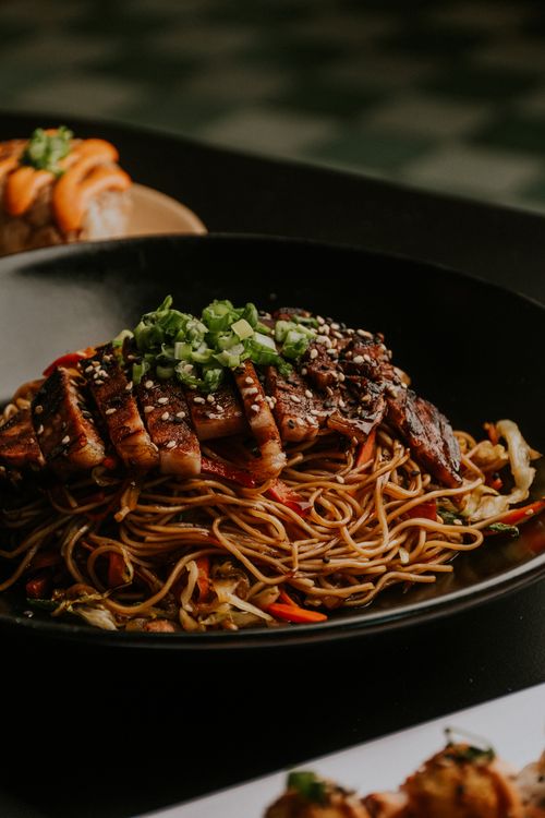 Free Savor the flavor of grilled chicken atop a bed of seasoned noodles, garnished with fresh herbs. Stock Photo