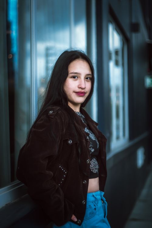 Free Stylish teenager in a jacket posing outdoors with a confident smile. Stock Photo