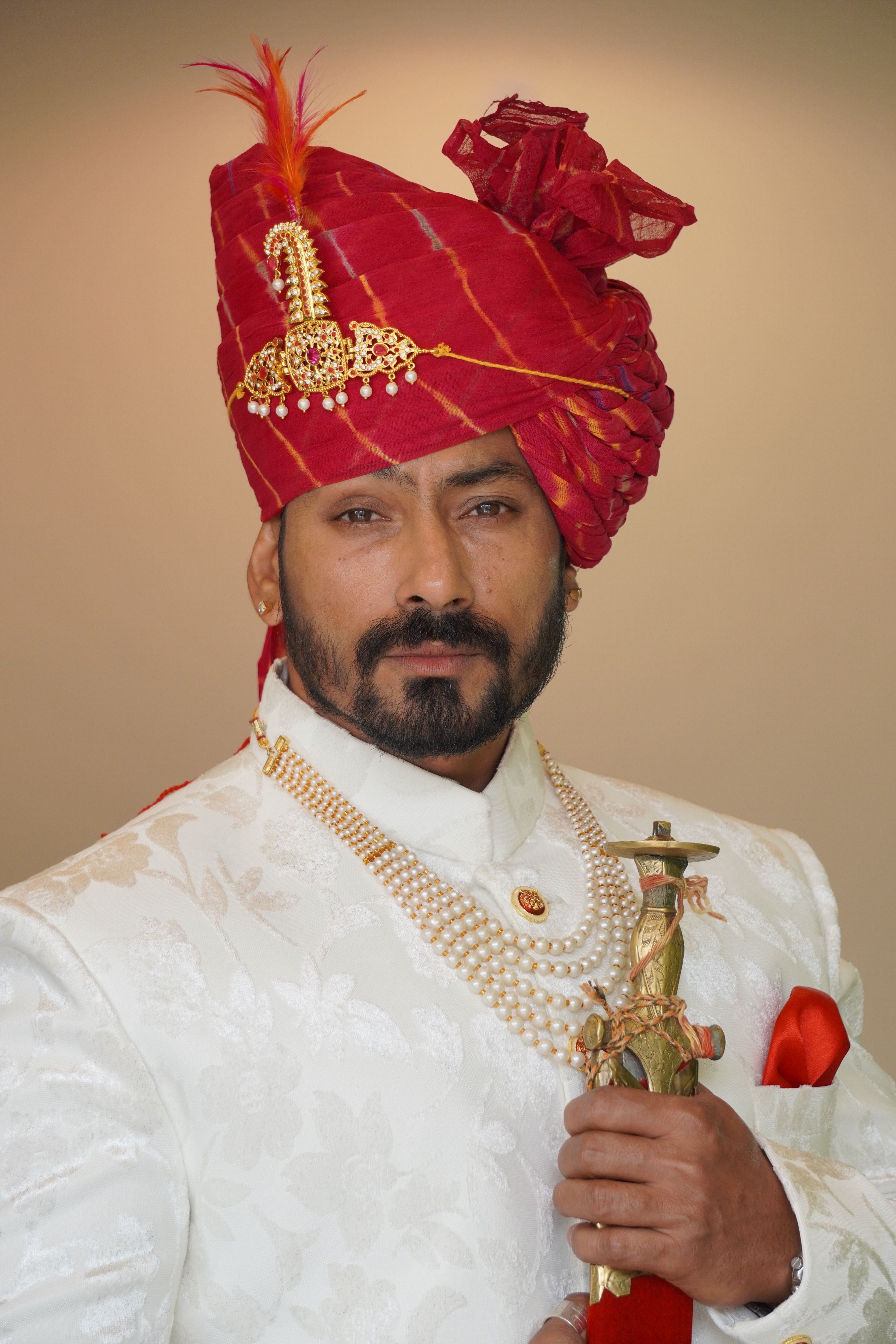 Elegant portrait of a man in traditional Indian clothing, holding a sword with a confident expression.