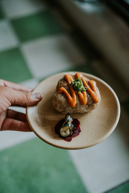 Close-up of a Man Holding a Plate with Onigiri