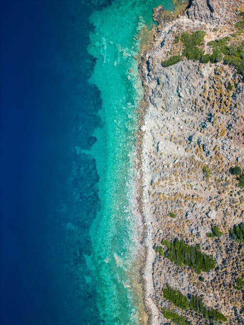 Aerial Footage of a Sandy Shore with a Navy Blue and Turquoise Sea