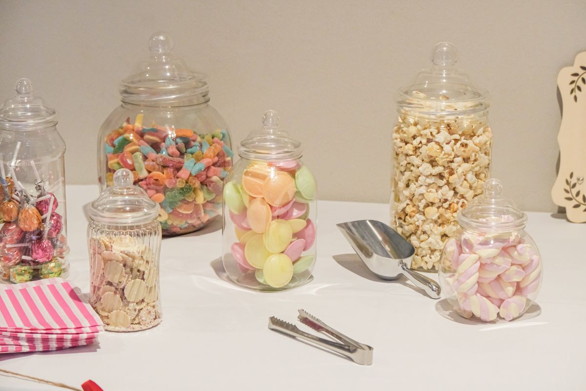 Colorful assortment of candies and popcorn in glass jars on a table, perfect for parties or events.