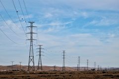 Transmission towers in a desert landscape with blue skies, showcasing energy infrastructure.