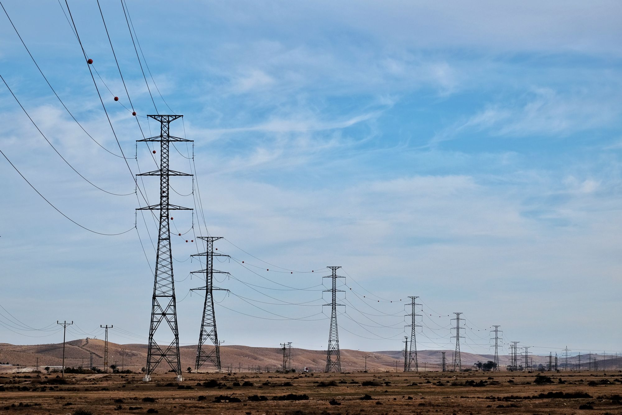 Torres y líneas de transmisión eléctrica cruzando un paisaje desértico al atardecer