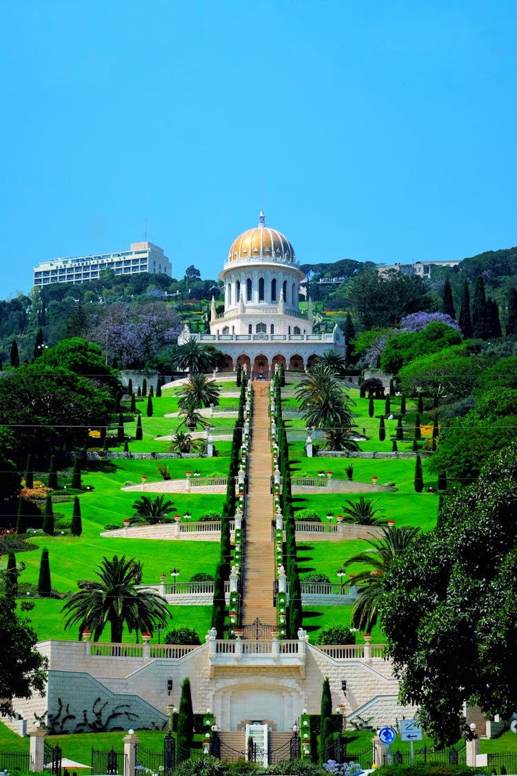 Symmetrical View Of A Green Garden And A Golden Dome Monument On Top Of The Hill