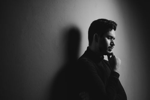 Free Black and white portrait of a young man in deep thought with strong shadow and contrast. Stock Photo