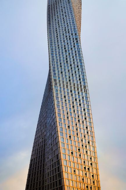 The iconic Cayan Tower's twisting design set against a serene Dubai sky.