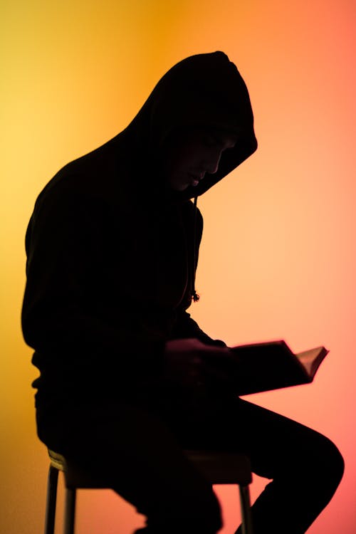 Free Silhouette Photo Of Person Sitting On Chair While Reading Stock Photo