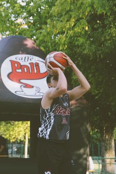 Young athlete playing basketball in an outdoor park during summer.