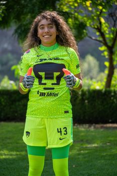 Youthful female soccer player in vibrant green uniform on a sunny day outdoors.