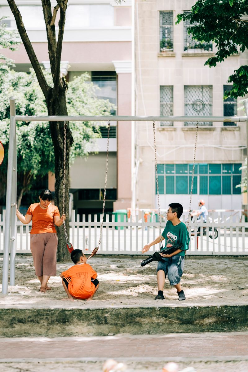 Mother watching her children on playground swings