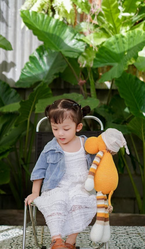 Free A Little Girl Holding a Teddy Bear and Sitting Outside  Stock Photo