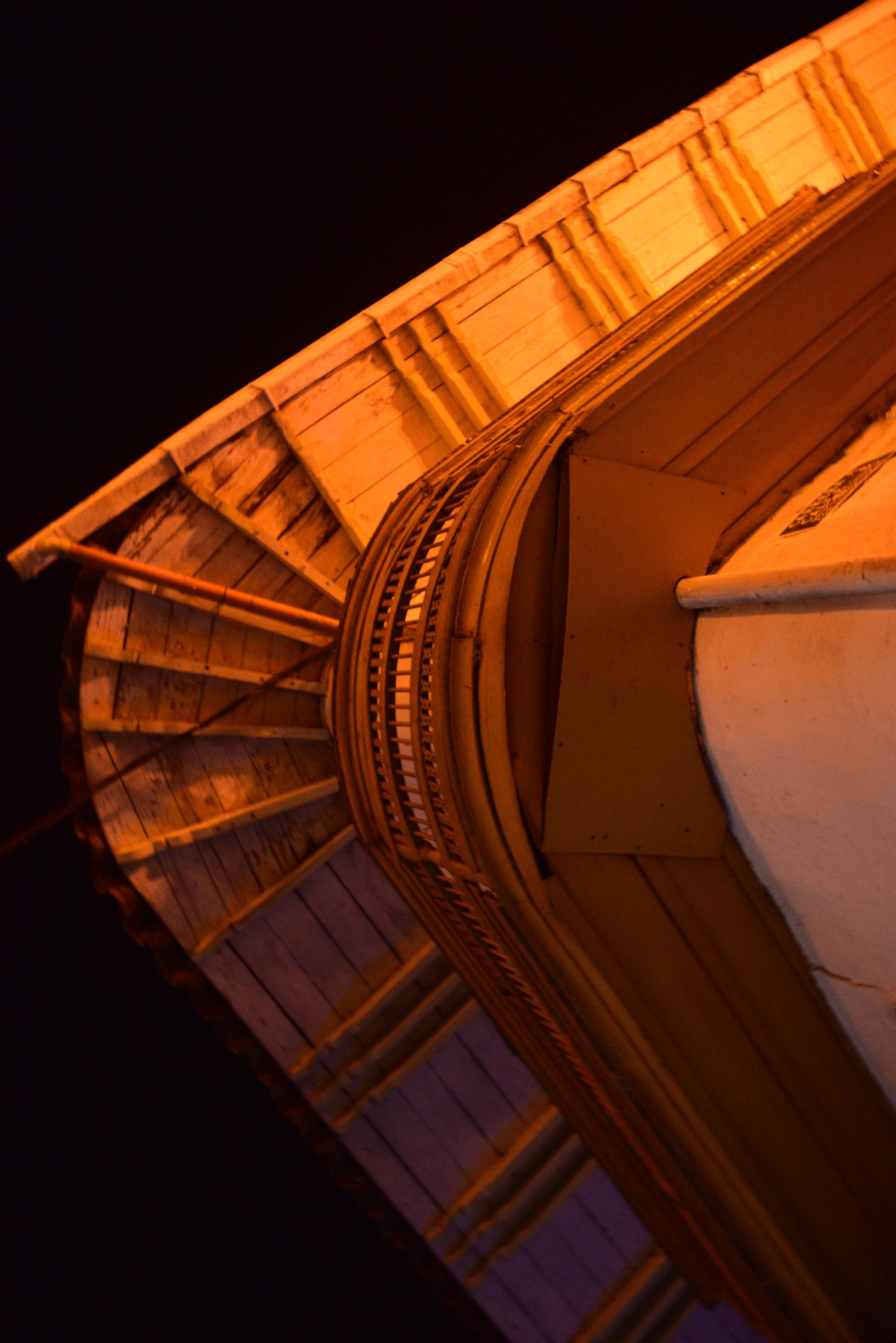 A close-up view of an illuminated architectural eave at night, showcasing intricate patterns and textures.