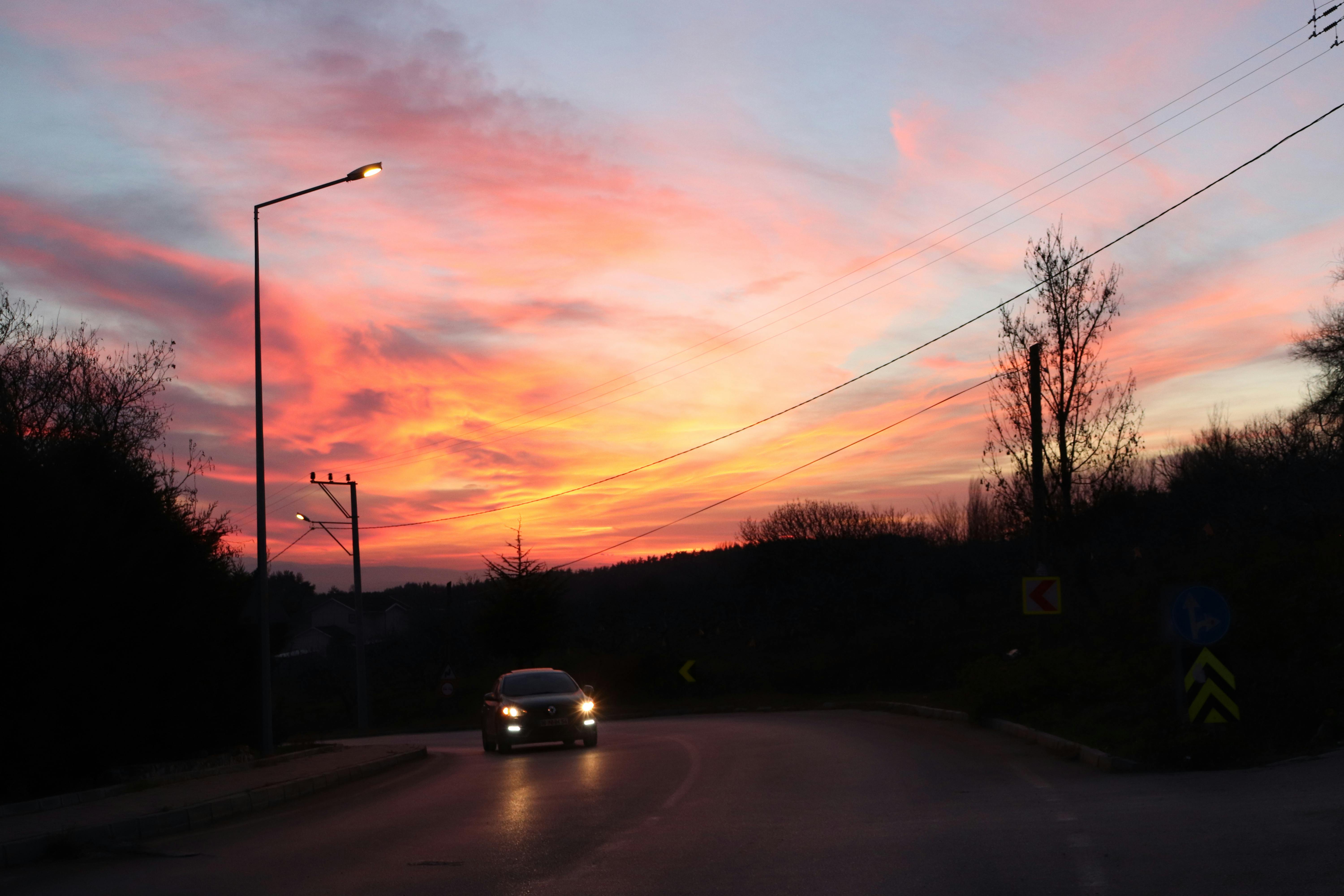 A car drives on a rural road at sunset with vibrant colors in Bursa, Türkiye.