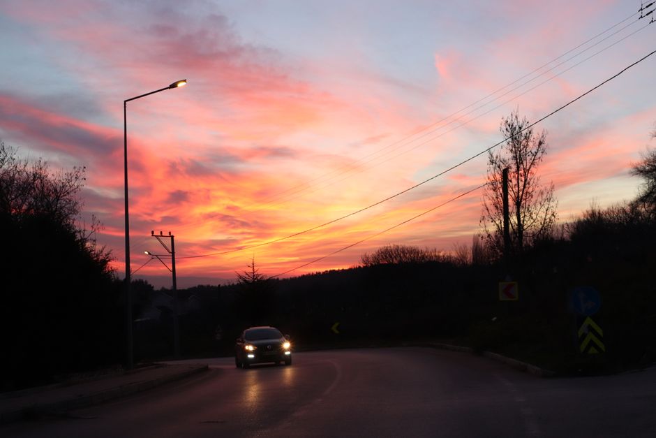 A car drives on a rural road at sunset with vibrant colors in Bursa, Türkiye.