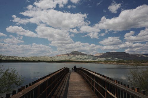 Free People Standing on Wooden Jetty with View of Mountains Stock Photo