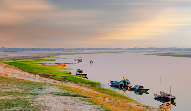 Boats On Riverbank At Sunset