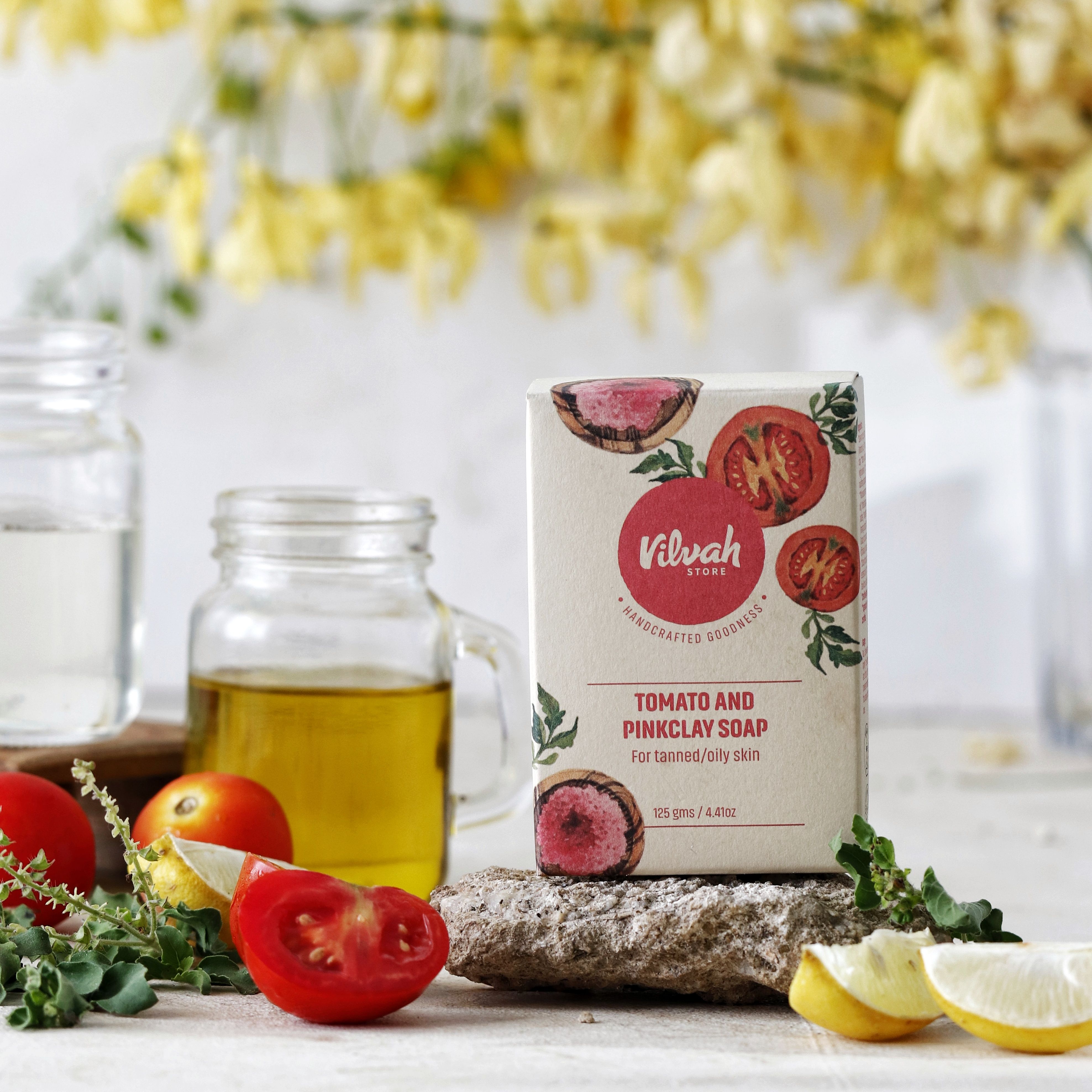 Tomato and pink clay soap surrounded by fresh ingredients for skin care.