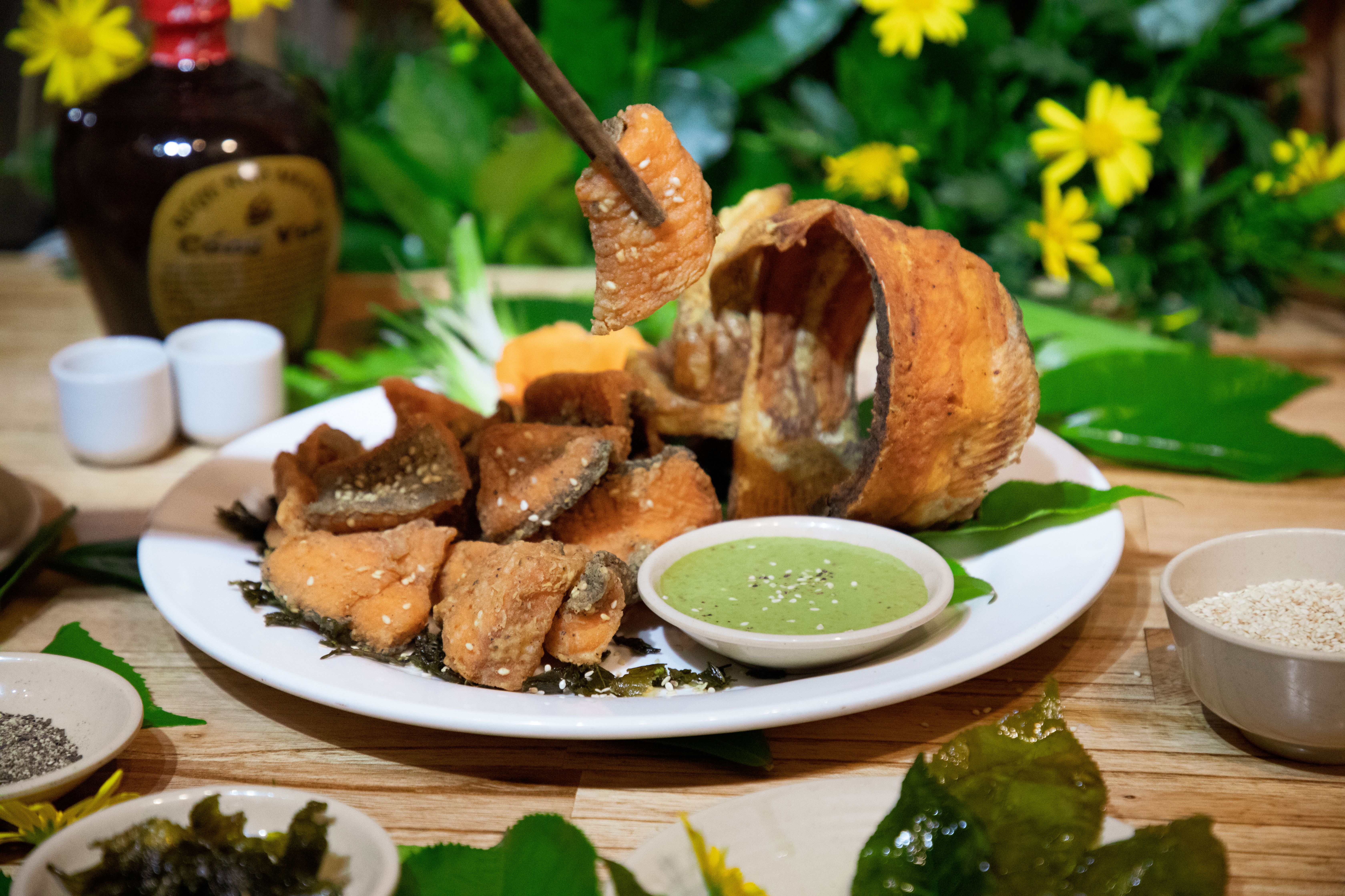 Delicious fried fish pieces served with green dipping sauce and fresh herbs.