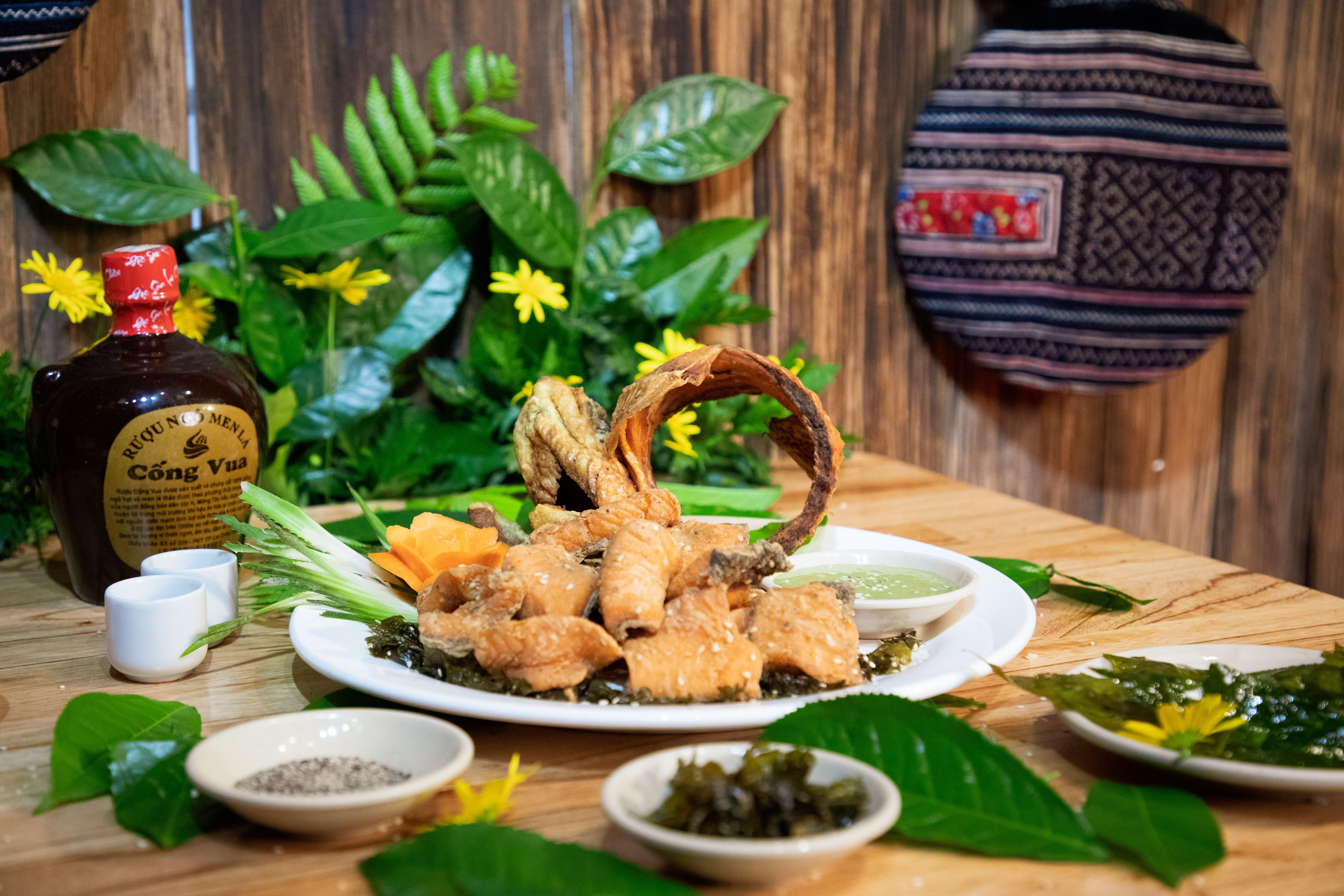 Fried fish and herbs on a plate with Vietnamese decorations, indoors.