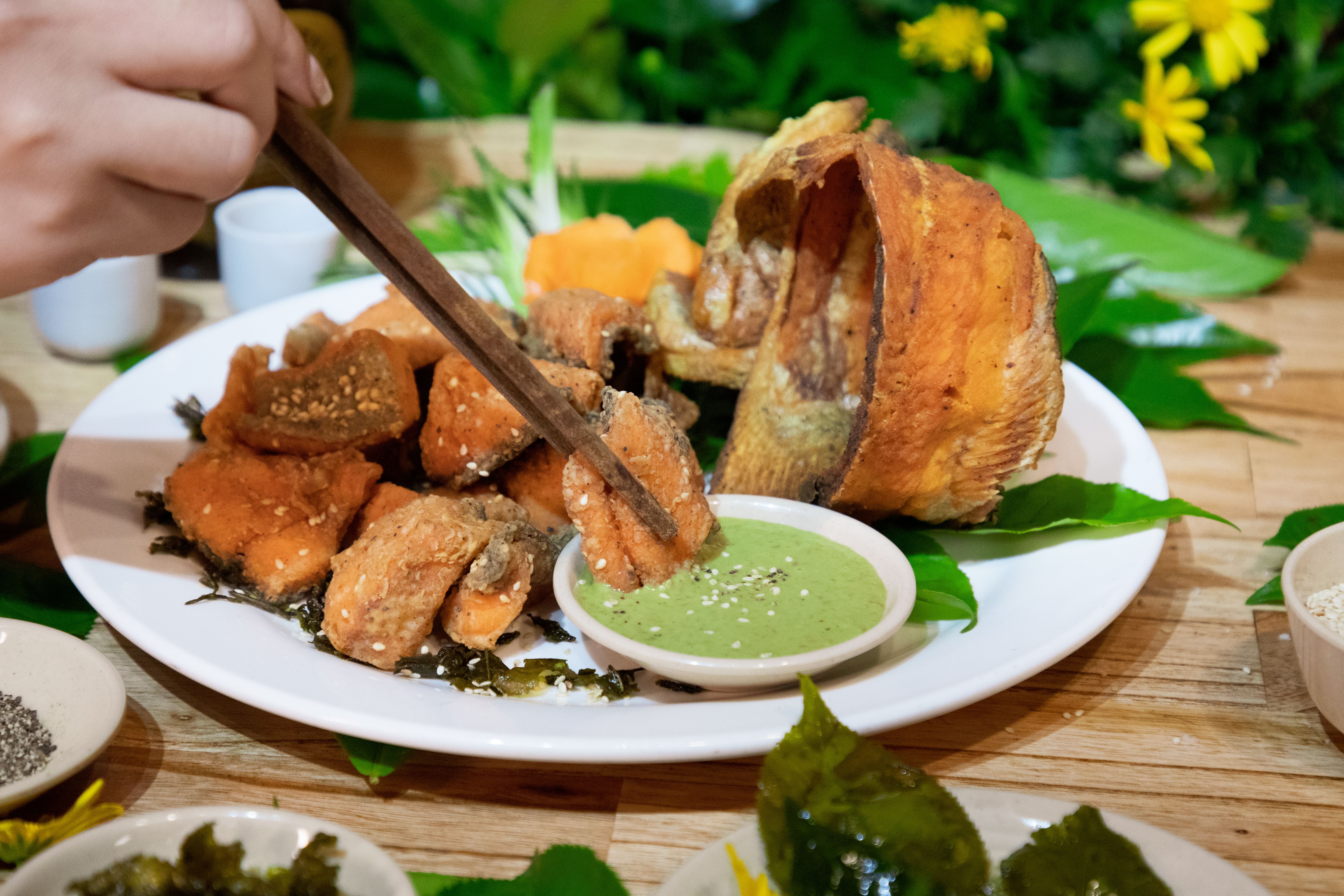Delicious crispy fried fish served with green dipping sauce, perfect for a gourmet meal.