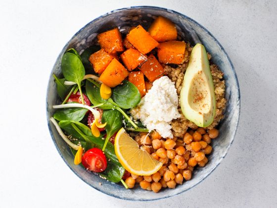 Bowl of roasted sweet potato, quinoa, chickpeas, avocado, spinach, feta and lemon slice
