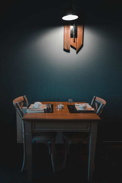 Free A cozy and modern dining table setup for two under a soft lamp light, indoors. Stock Photo