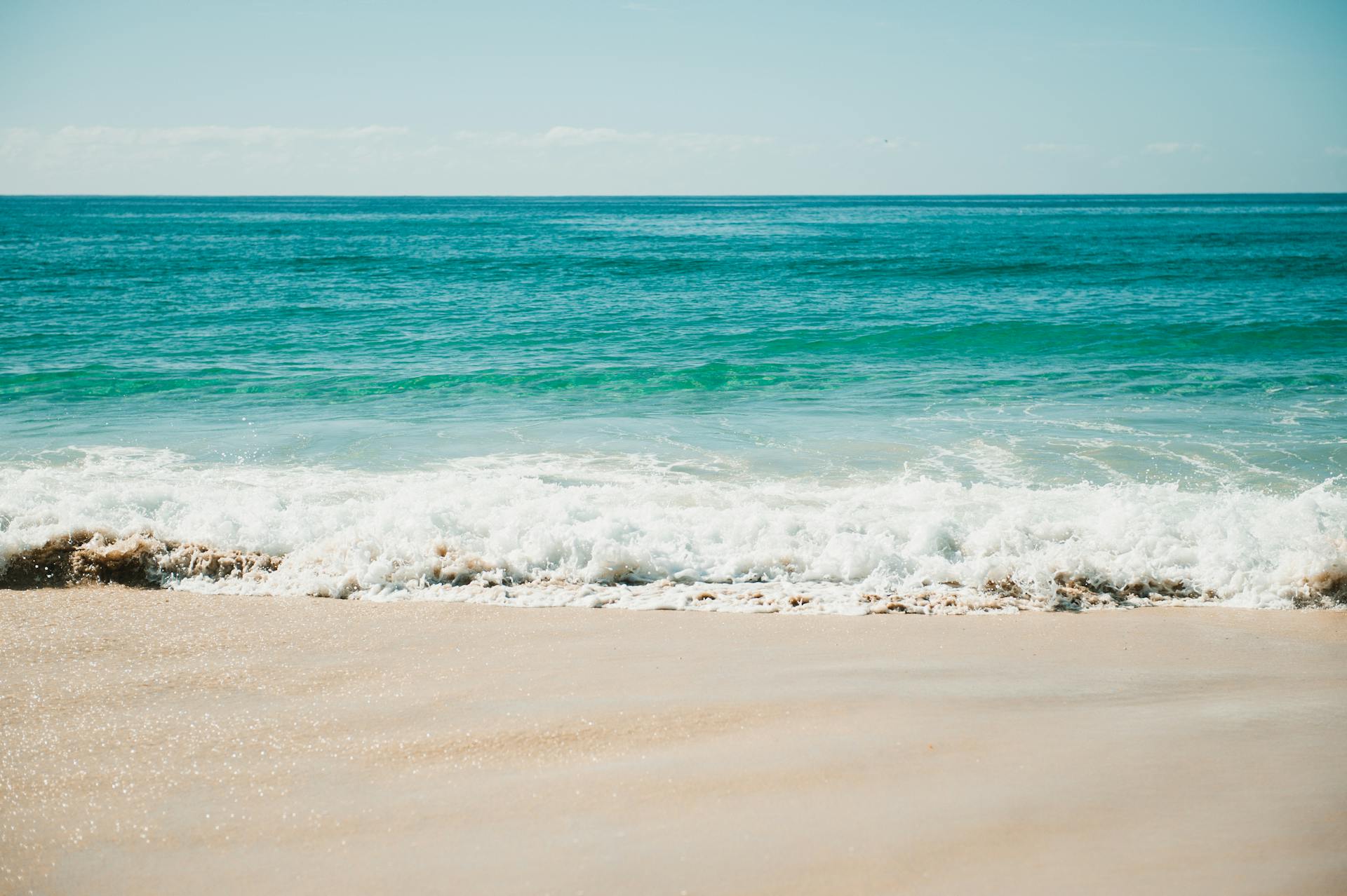 Bright sunny day at Gold Coast beach with gentle waves and clear blue ocean.