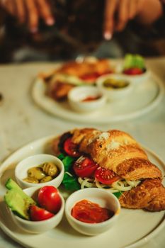 Tasty croissant sandwich with fresh veggies and sauces, perfect breakfast choice.