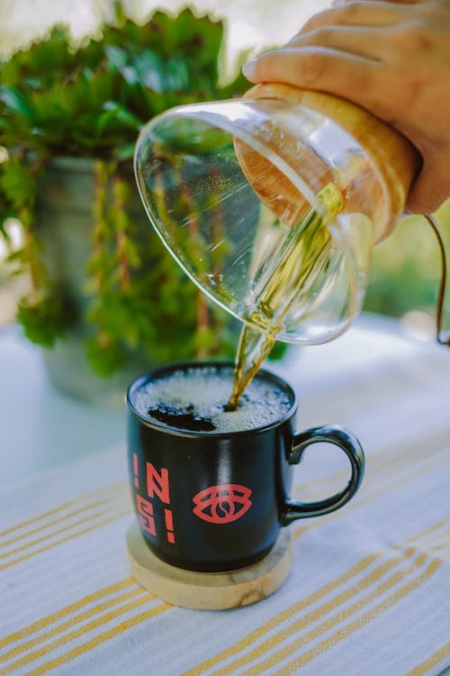 Free Close-up of Person Pouring Coffee from a Glass Pot into a Cup  Stock Photo